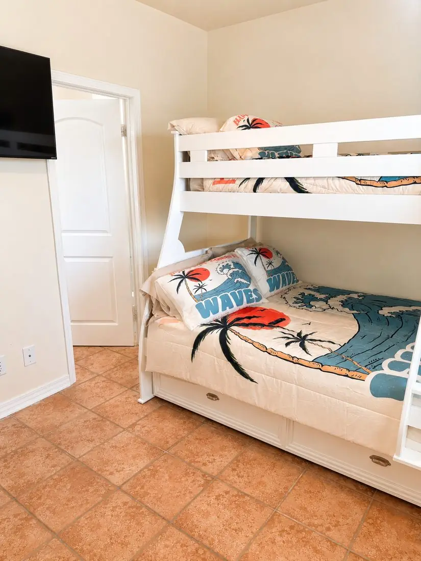 Bunk room with trundle bed, TV, and wave-print bedding